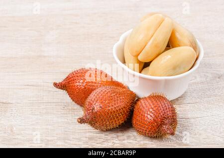 Salak Palm , waive or snake fruit in wooden dish on table. Stock Photo