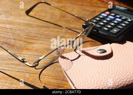 glasses, calculator and wallet on wooden table. Business profit concept Stock Photo