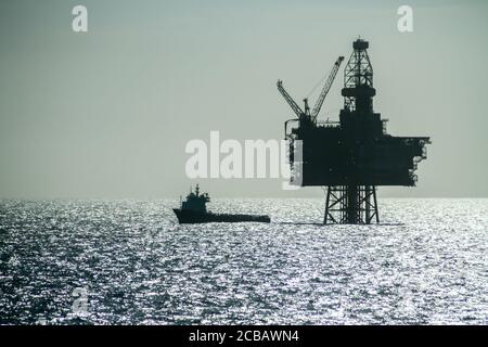 NORTH SEA, NORWAY - 2011 APRIL 23. Silhouette of an Offshore Supply Vessel alongside oil platform Ringhorn in the North Sea Stock Photo