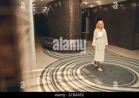Happy smiling lady in white bathrobe posing at the photo camera Stock Photo