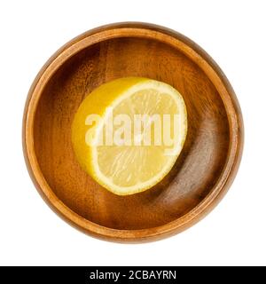 Fresh and ripe half lemon in a wooden bowl. Cut yellow edible citrus fruit, Citrus limon. Lemon juice is used for culinary purposes and for cleaning. Stock Photo