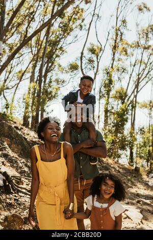 Family with two kids on a mountain trail. Family hiking through forest and smiling. Stock Photo