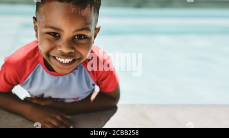 Closeup of cute boy on the edge of a swimming pool. Small boy in a pool looking at camera and smiling.