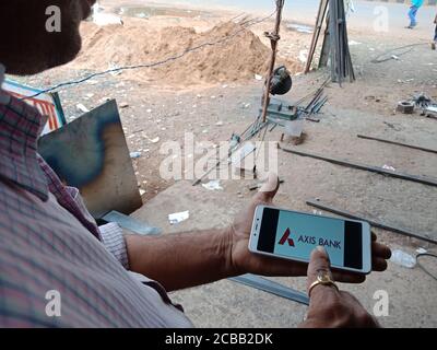DISTRICT KATNI, INDIA - JUNE 02, 2020: An indian man holding smart phone with displaying axis bank online logo on screen, modern banking education con Stock Photo