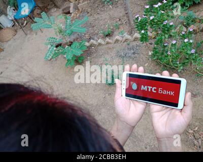 DISTRICT KATNI, INDIA - JUNE 02, 2020: An indian woman holding smart phone with displaying MTC Federal credit bank logo on screen, modern banking educ Stock Photo
