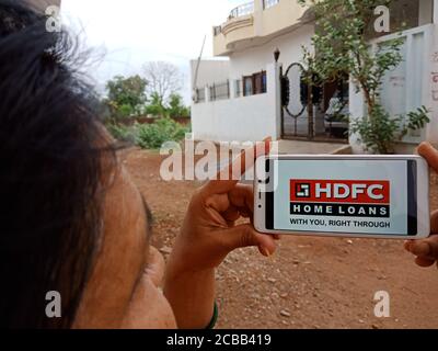 DISTRICT KATNI, INDIA - JUNE 02, 2020: An indian woman holding smart phone with displaying Housing Development Finance Corporation logo on screen, mod Stock Photo