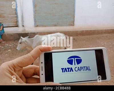 DISTRICT KATNI, INDIA - JUNE 02, 2020: An indian woman holding smart phone with displaying Tata Capital Financial services company logo on screen, mod Stock Photo