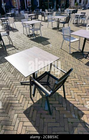Empty terrace of a closed restaurant in The Netherlands with space between tables and chairs during coronavirus restrictions waiting to reopen Stock Photo