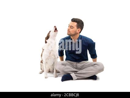 Pet owner sitting on the floor with his howling dog, isolated on white Stock Photo