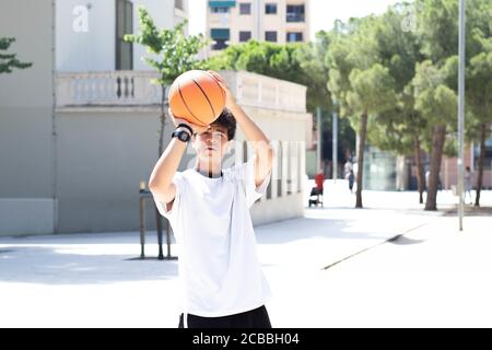 Afro teenage boy throwing a ball into a basket on the basketball court Stock Photo