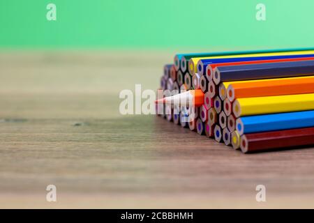 close up view of colored pencils stacked with an orange pencil turned upside down spilling out Stock Photo