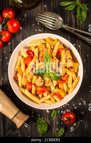 Pasta with chicken and vegetables at wooden table. Stock Photo