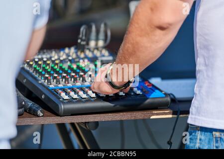 DJ mixer controller. DJ hand control music in open air party. Professional audio equipment for rock concert, night club dance party or wedding. Stock Photo