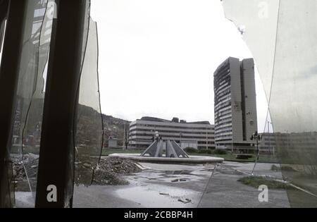 12th April 1994 During the Siege of Sarajevo: the battle-scarred Assembly Building viewed through a broken window of the Unis Towers complex. Stock Photo