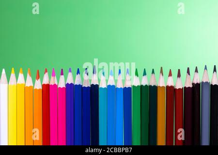 close up of colored pencils aligned vertically with green background Stock Photo