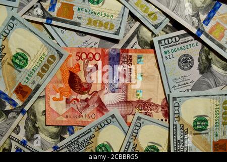 Kazakhstan 5000 tenge banknote on top of US dollars national currency, top view of mixed american dollar banknotes. Kz paper money. Tenge and US dolla Stock Photo