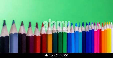 close up view of colored pencils aligned vertically with green background, panorama Stock Photo