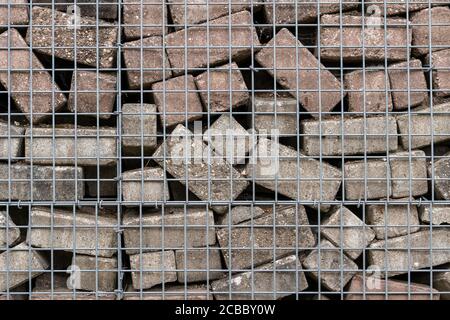 Stone wall built of concrete bricks and metal mesh Stock Photo