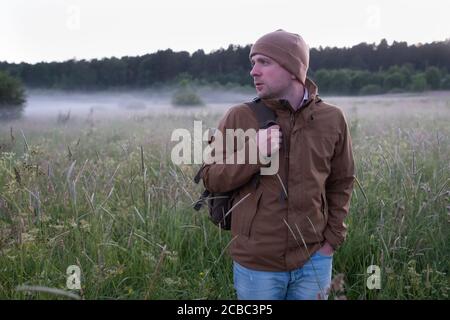 Man walking in a misty meadow hiking in the evening. Stock Photo