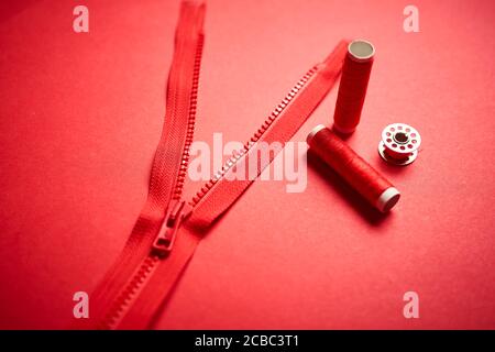 threads and zipper on a red minimalistic background Stock Photo