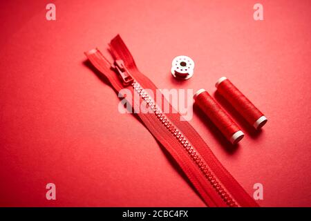 threads and zipper on a red minimalistic background Stock Photo