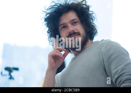 Satisfied with work done. Happy young man working on laptop while sitting at his working place in office Stock Photo