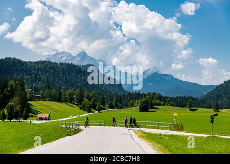 People bike in the green nature near the high mountains on a sunny cloudy day Stock Photo