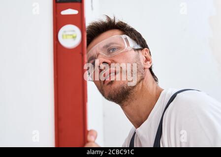 Male worker checking level of the wall with the bubble level tool. Renovation concept Stock Photo