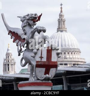 Symboic Griffin or Gryphon statue marking the boundary entrance to the CIty of London, on Blackfriars Bridge, with the dome of St Pauls cathedral Stock Photo