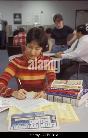 Austin Texas USA, 2002: Asian-American woman, 23, searches for entry-level position using state employment center resources and local newspaper.  Model Release. ©Bob Daemmrich Stock Photo