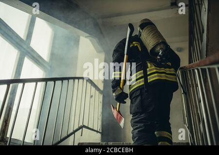 young extinguisher with hammer go to save and protect wearing uniform, on the landing Stock Photo