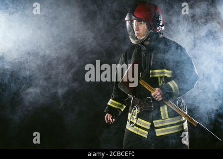 strong confident fireman saving and protecting from fire, wearing protective helmet and suit, working in fire station Stock Photo