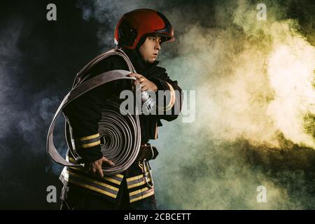 young fire fighter holding rope in hands ready to save and protect from fire Stock Photo