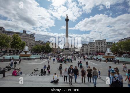 Tourists and pigeons seen on general view of Trafalgar Square from the North Terrace towards Nelson's Column in summer. Stock Photo