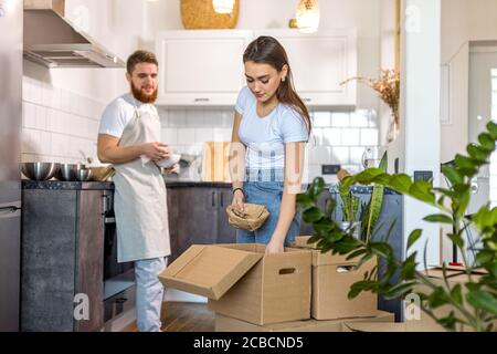 young caucasian happy couple unpacking cardboard boxes after moving in new house. couple very happy to get keys from new apartment Stock Photo