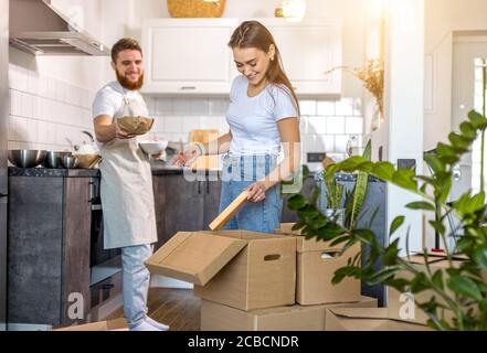 happy moving into a new apartment. beautiful cheerful caucasian married couple unpacking cardboard boxes with tableware in the kitchen Stock Photo
