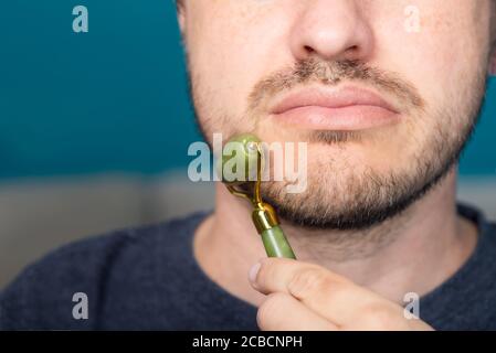 Bearded man is using jade face roller Stock Photo