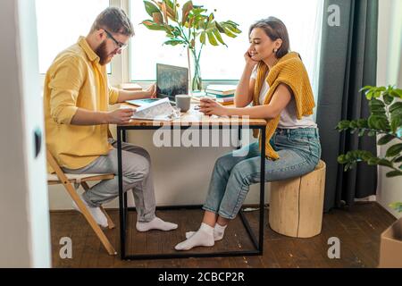 cute caucasian wife look at working husband with love, married couple at home. man sit using laptop, at freelance Stock Photo