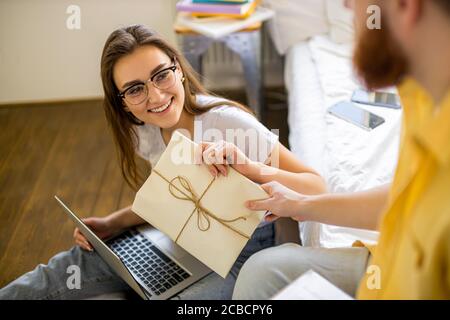 young caucasian couple preparing invitations for wedding at home. beautiful couple sit at home using laptop, they sort and prepare letters for guests Stock Photo
