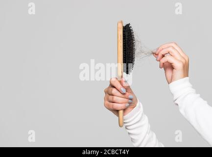 Hair loss problem, postpartum period, menstrual disorder, stress. Many hair fall after combing in hairbrush. Female untangles her hair with a comb, co Stock Photo