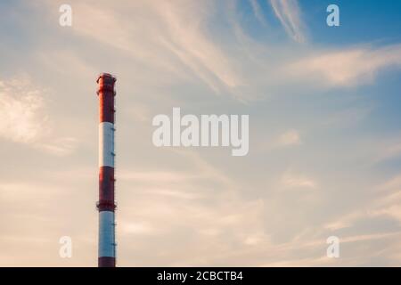 Red and white striped plant pipe at sunset against blue sky with copy space Stock Photo
