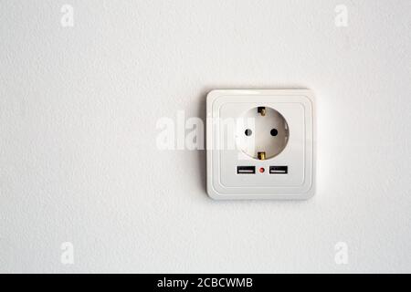 universal power socket European standard 220 volt with two connectors usb for charging mobile devices. socket white plastic on a white wall with copy Stock Photo