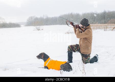 young man is aiming at a bird while dog is waiting for a shot. side view shot.killing animals Stock Photo