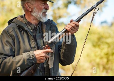 Senior man seen prey and going to shoot. Forest background Stock Photo
