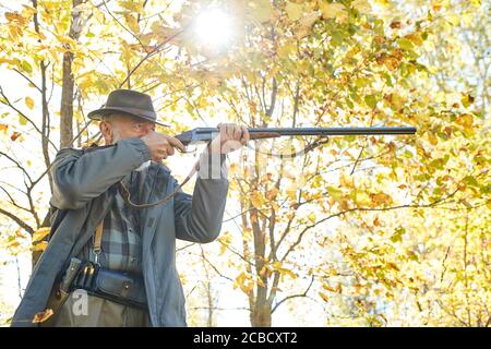 Senior hunter in forest aim his rifle at animal, trophy Stock Photo