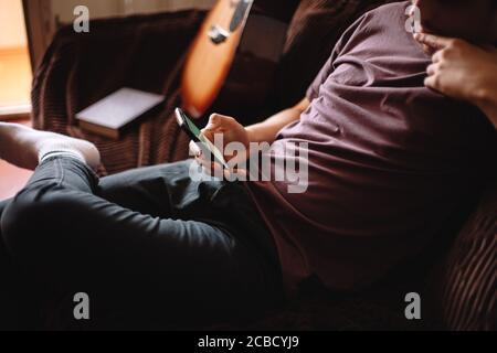 Thoughtful young man using smart phone while sitting at home Stock Photo
