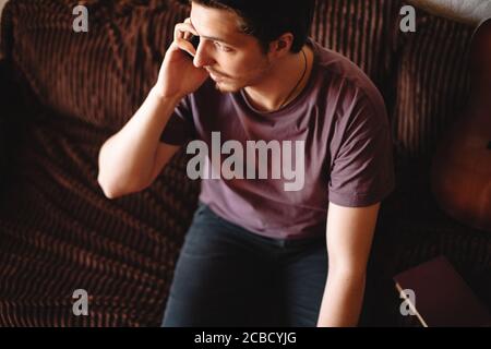 Young man talking on mobile phone sitting on sofa at home Stock Photo