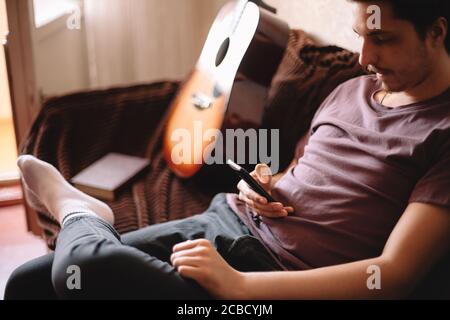 Serious young man using smart phone while sitting at home Stock Photo