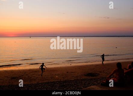 Sunset beachgoers at Totland Bay on the Isle of Wight Stock Photo