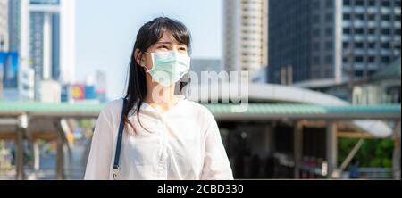 Banner of Asian businesswoman in white shirt going to work in pollution city she wears protection mask prevent PM2.5 dust, smog, air pollution and COV Stock Photo
